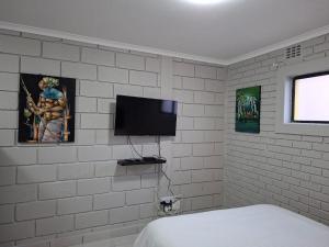 a bedroom with a tv on a white brick wall at Grace Villas 31 in East London