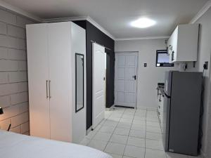 a kitchen with white cabinets and a black refrigerator at Grace Villas 31 in East London