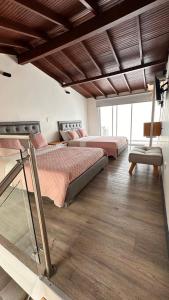 two beds in a room with wooden floors at Hotel Plaza El Santuario in Santuario