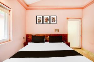 德拉敦Hotel O Amodam Resort的卧室里有一张床，墙上挂着两幅画