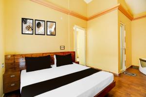 德拉敦Hotel O Amodam Resort的卧室里有一张床，墙上挂着两幅画