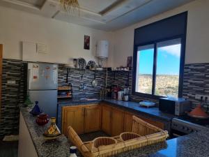 a kitchen with a counter and a refrigerator and a window at Reda House in Ikouzza