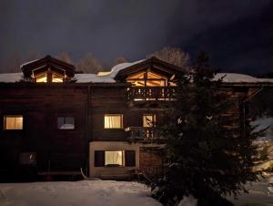 a house with lights on in the snow at night at Silva: The Alpine Chalet in Livigno