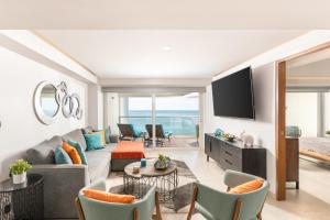 a living room with a couch and a tv at Luxury 2-Bedroom Beachfront Oasis – Two Balconies to Soak in the Views in Puerto Vallarta