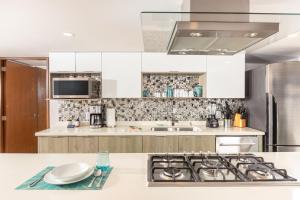 a kitchen with white cabinets and a stove top oven at Luxury 2-Bedroom Beachfront Oasis – Two Balconies to Soak in the Views in Puerto Vallarta