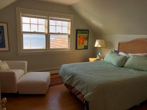 a bedroom with a bed and a chair and a window at Oceanfront - Downtown in historic New England in Salem