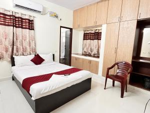 チェンナイにある7 Hills Service Apartmentsのベッドと椅子のある寝室