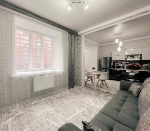 a living room with a couch and a kitchen at Евродвушка в ЖК Ирина in Pavlodar