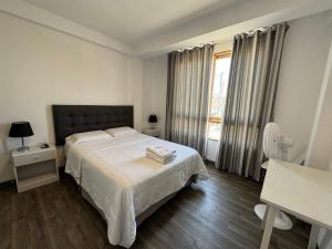 a white bedroom with a bed and a window at Betania in Paracas