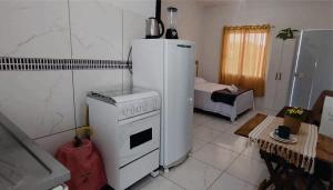 a kitchen with a white stove and a refrigerator at Kitinet completa com varanda Praia de Caiobá in Matinhos