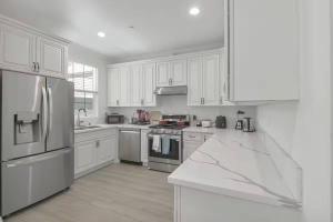 une cuisine avec des armoires blanches et des appareils en acier inoxydable dans l'établissement Stylish Pasadena Stay Near Old Town & Rose Bowl, à East Pasadena