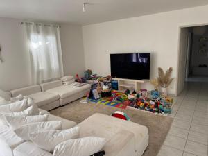a living room with white furniture and a flat screen tv at Maison verdoyante in Monteux