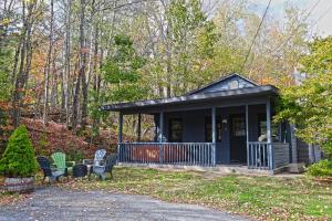 a small black cabin with chairs in the woods at Private Hot tub new 2 Bedroom Home in Catskills in Elka Park