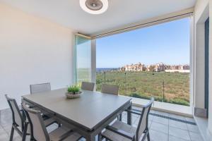 Un comedor con mesa y sillas y una gran ventana. en Los Flamencos, en Isla Canela
