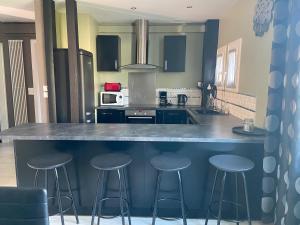 a kitchen with three bar stools at a counter at Maison Maurice in Le Mans