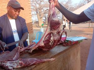 een man die een dood dier op een tafel snijdt bij P plus lodge in Iringa