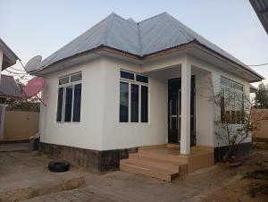 een klein wit huis met een grijs dak bij P plus lodge in Iringa