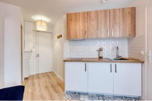 a kitchen with white cabinets and a wooden counter top at Great Cozy Studio - Paris in Bagnolet