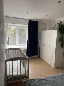 a bedroom with a crib and a large window at Nature Love Apartment in Liepāja