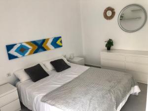 a white bedroom with a bed and a mirror at La Casilla del Molino in Almodóvar del Río