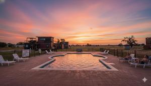 a pool with people sitting in chairs in front of a sunset at Fredericksburg Stay W Patio, Fire Pit & Hot Tub in Fredericksburg
