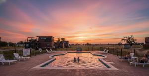 Una piscina con gente y una puesta de sol de fondo. en New Pool, Hot Tub, Patio, Pickleball, Cornhole, en Blumenthal