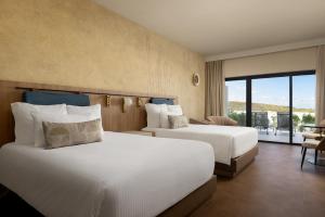a hotel room with two beds and a balcony at Secrets Baby Beach Aruba Adults Only in Ceru Colorado