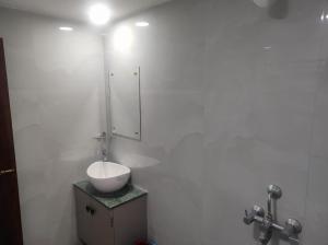 een witte badkamer met een wastafel en een spiegel bij GoFam in Dibrugarh