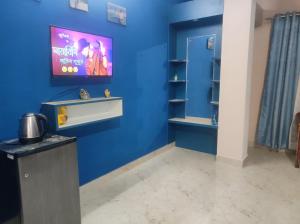 een blauwe kamer met een tv aan een blauwe muur bij GoFam in Dibrugarh
