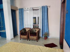 een slaapkamer met 2 stoelen en een raam bij GoFam in Dibrugarh