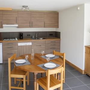 Una cocina con una mesa de madera y sillas con copas de vino. en Appartement des Crêtets, en Megève