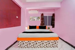 1 dormitorio con 1 cama grande en una habitación rosa en Hotel O The Triotel Inn, en Dhanbād