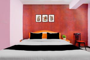 Un dormitorio con una cama grande y una pared roja. en Hotel O The Triotel Inn, en Dhanbād 24 fotos más
