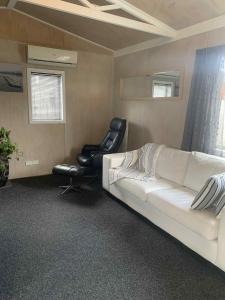 - un salon avec un canapé blanc et une chaise dans l'établissement Hosts on the Coast Pawprint Cabins, à Whitianga