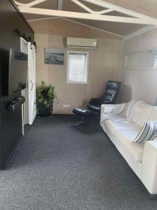 une chambre avec un lit et deux chaises dans une caravane dans l'établissement Hosts on the Coast Pawprint Cabins, à Whitianga