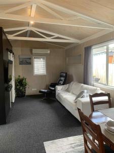 un salon avec un canapé et des chaises dans une pièce dans l'établissement Hosts on the Coast Pawprint Cabins, à Whitianga