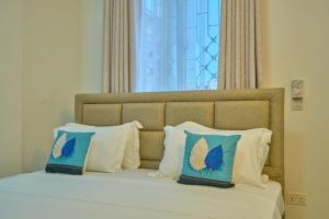 a bed with blue and white pillows and a window at Royal Suites in Mombasa