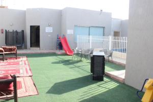 Un patio con un parque infantil con un tobogán rojo. en شاليهات ديم لايت, en Az Zulfi