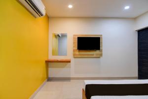 a room with a tv on a wall with a yellow wall at Hotel O MOODY MOON.02 in Bālianta