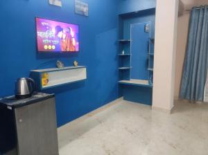 een blauwe kamer met een tv aan een blauwe muur bij GoFam in Dibrugarh +2 foto's