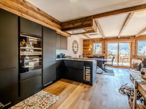 une cuisine avec des armoires noires et du parquet dans l'établissement Appartement de prestige spacieux et lumineux avec sauna et parking inclus - FR-1-598-48, aux Gets