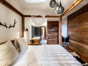 une chambre avec un lit blanc et un mur en bois dans l'établissement Appartement de prestige spacieux et lumineux avec sauna et parking inclus - FR-1-598-48, aux Gets