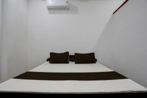 a bed in a white room with two black pillows at SPOT ON S.M. HOTEL in Ghoghāpur