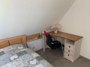 a bedroom with a desk with a bed and a chair at Über den Dächern der Stadt in Bremervörde