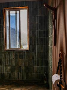 a bathroom with a window and green tiled walls at refugio el bagual in Futaleufú