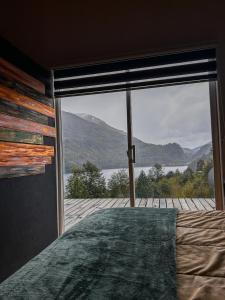 a bedroom with a large window looking out at a lake at refugio el bagual in Futaleufú +11 photos