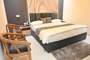 a bedroom with a large bed and a chair at Hotel Glumol in Roorkee +6 photos