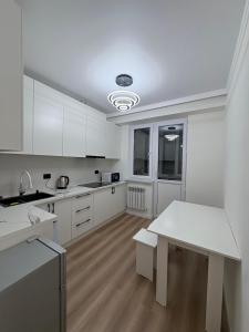 eine Küche mit weißen Schränken und einem weißen Tisch in der Unterkunft Sunny Home Apartment in Almaty + 20 Fotos