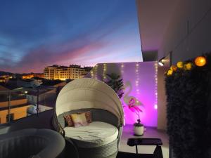 a white chair on a balcony with purple lights at ÁTICO RILQUE, Apartamentos Independientes con Jacuzzi Privado y Terraza en Ronda in Ronda
