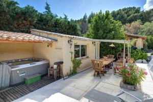 un patio con bañera de hidromasaje, mesa y sillas en Les Gargoulettes, en Lauris